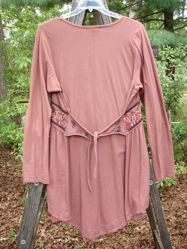 Barclay Decora Banded V Neck Dress Rouge Size 1 displayed on a wooden rack, showcasing its deep V neckline, vertical pleats, and sectional panels. Made from organic cotton, perfect for fall.