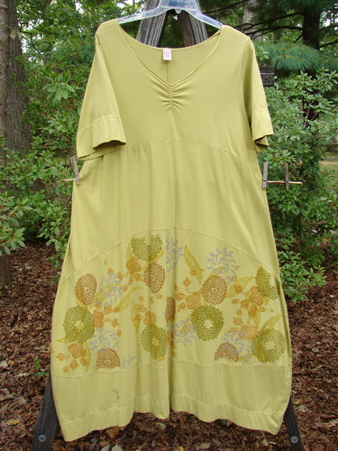 Barclay Gather Sectional Banded Petal Dress Whimsical Garden Split Pea Size 1 on a clothesline, showcasing a V-shaped neckline, dippy hemline, and whimsical garden-themed floral design.