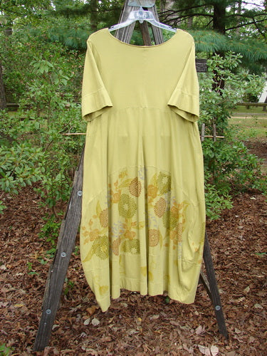 Barclay Gather Sectional Banded Petal Dress Whimsical Garden Split Pea Size 1 displayed on a rack, showcasing its whimsical garden theme and unique detailing like the V-shaped neckline and varying hemline.