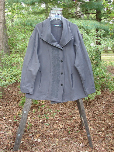 Barclay Interlock Side Button Jacket Sky Plum Size 2 displayed on a wooden stand, showcasing its unique wide sleeves, double slit pockets, and off-set front button line.