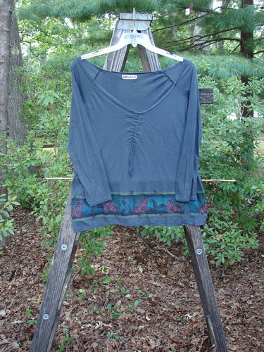 Barclay Batiste Decora Gather Top Gourd Farm Navy Size 1 displayed on a wooden rack, showcasing a deep V neckline, vertical drawcord accent, and unique gourd farm theme paint.