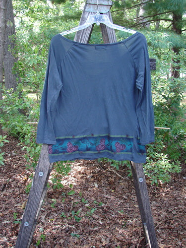 Barclay Batiste Decora Gather Top Gourd Farm Navy Size 1 displayed on a wooden stand, showcasing a deep V-neckline, vertical front drawcord, shoulder pleats, and boxy shape with farm-themed paint detailing.