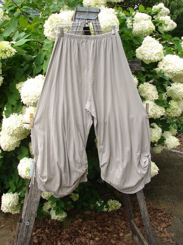 Bluefishfinder.com Barclay Crop Tie Bottom Crop 4 Square Pant in unpainted sand cloud, size 0, with a loose cropped silhouette, gathered elastic waist, and tied hem openings. The soft, draped fabric hangs from a weathered wooden ladder against white hydrangeas and green leaves.