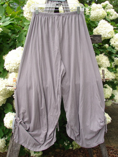 Bluefishfinder.com Barclay Crop Tie Bottom Crop 4 Square Pant in unpainted plum cloud, size 0, shown as loose draped crop pants with a gathered elastic waist and tie hems. The soft gray-lavender fabric hangs in wide rounded legs against a leafy floral backdrop.