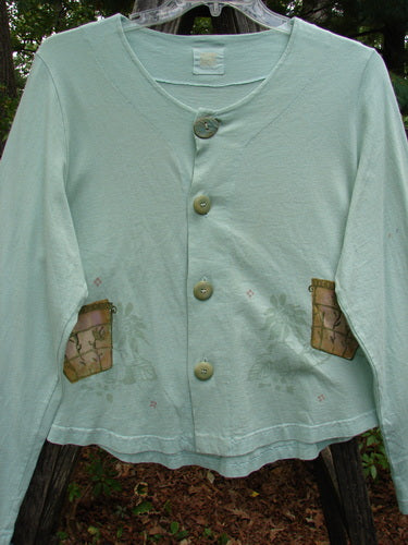 1999 Coffee Top Flowerpot Mint Size 1 with ceramic buttons, drawcord back, and a rounded hemline from Blue Fish's Spring Collection, showcased on a model's arm.