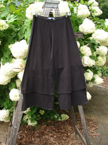 Bluefishfinder.com Barclay Cotton Lycra Crop 2 Petal Pantaloon in unpainted black, size 0, with a layered cropped silhouette and soft draped cotton-lycra fabric. It hangs from a wooden ladder outdoors, framed by white hydrangeas and green foliage.