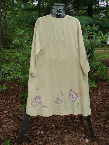 1999 Cream and Sugar Coat Pitcher Plantain OSFA displayed outdoors, featuring a long, flowing design with deep side pockets, a V-shaped neckline, and a large single shell button closure.