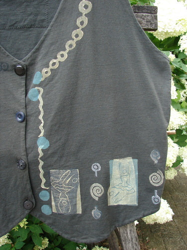 Bluefishfinder.com 1993 The Vest Dancer in black sand, size 2, a sleeveless black vest with a soft matte texture, button front, and hand-drawn-looking pale blue and cream motifs along the front and hem. The cropped shape sits against leafy greenery, with layered stitching and printed square details adding a worn, artisanal feel.