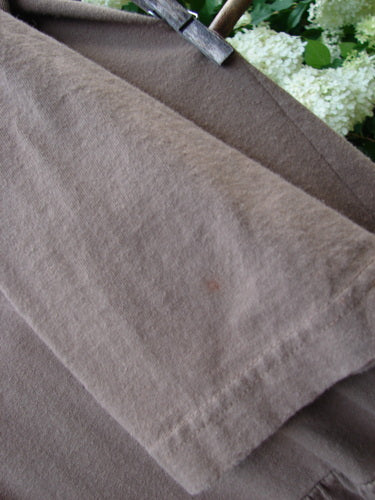Bluefishfinder.com 1995 Clothespin Jacket Butterfly Mudpie OSFA in muted brown fabric, shown in a close-up of layered panels with a soft, slightly worn texture and visible seam edges. A clothespin holds the garment near the top, with green foliage blurred behind it.