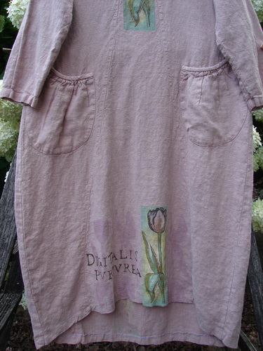 Bluefishfinder.com 1998 Botanicals Thostle Dress Single Tulip Mallow Size 1 in dusty mauve linen, with long sleeves, a relaxed straight silhouette, and large front patch pockets. Botanical print panels and faded lettering add a soft, vintage look.