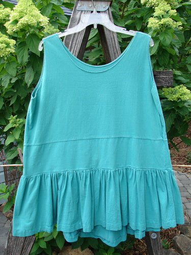 1990 Button Tier Top Unpainted Turq OSFA displayed on a clothes rack, showcasing its unique design with a drop waistband, gathered flounce, and ruffled hemline. Perfect condition, vintage collection.