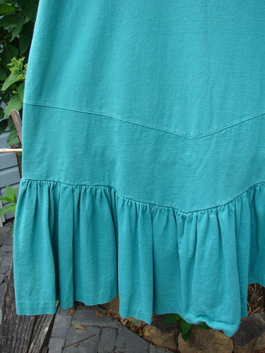 Close-up of the 1990 Button Tier Top Unpainted Turq OSFA, featuring a 6-inch drop waistband, gathered flounce, and V-shaped back dippy band, highlighting intricate textile patterns and detailed craftsmanship.