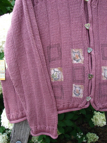 Bluefishfinder.com 1999 Triangle Cardigan Sweater Pitcher Clay Size 1 in dusty mauve knit, with a loose drape, ribbed trim, and iridescent triangle buttons. Square patch details and a soft, textured finish stand out against the leafy outdoor backdrop.