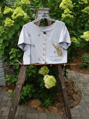 1994 Song Top Vintage Kitchen Garden Lavender Size 1 displayed on a hanger, highlighting its wide boxy shape, shallow neckline, vintage buttons, oversized front pocket, and garden-themed paint details.