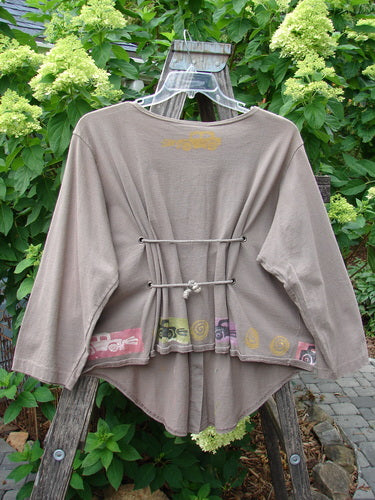 1993 Tie Back Jacket Car Bay Leaf OSFA displayed on a wooden swing, showcasing vintage buttons, shallow neckline, drop shoulders, and unique front-back hemline with antique car theme paint and double drawcord back.