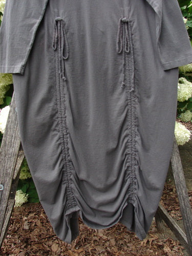 Bluefishfinder.com 1998 Cornucopia Dress Fall Garden Eggplant Size 1 in deep eggplant gray, a loose draped dress with three-quarter sleeves, gathered vertical seams, and a ruched hem. The soft, matte fabric hangs in a rounded silhouette against an outdoor garden backdrop.