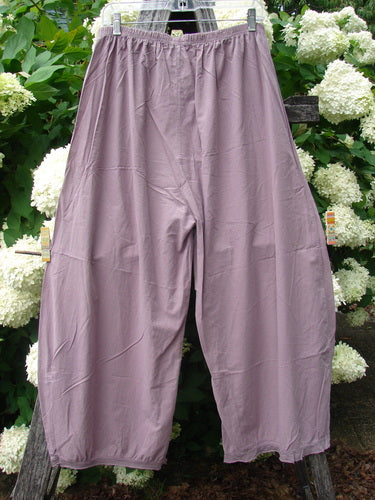 Bluefishfinder.com Barclay Batiste Tiny Flutter Pocketless Pant in unpainted dusty plum, a loose, wide-leg pair with a softly crinkled matte finish and elastic waistband, hanging front-facing against white hydrangeas and dark wood.