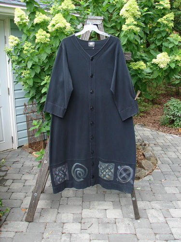 2000 Interlock Glassgow Coat Dress Celtic Black Size 1 displayed on a clothes rack, showcasing oversized buttons, a wide swingy hem, and distinctive Celtic-themed paint.
