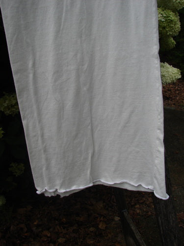 Barclay Raw Edge Wide Leg Pocketless Pant in unpainted natural, size 1, shown in a light gray drape with a wide leg and raw hem. The fabric looks soft and lightly wrinkled, hanging against dark greenery in subdued outdoor light.
