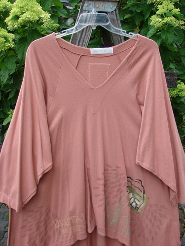 1998 Botanicals Bell Flower Top Magnolia Size 2 displayed on hanger, showcasing its belled A-line shape, upward scooped front hem, rounded neckline, and blue fish patch on back.