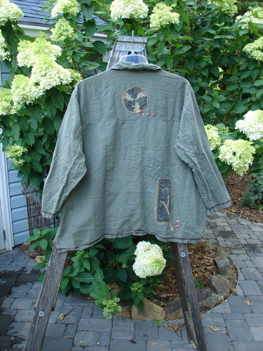 Barclay Hemp Cotton Metal Button Workshirt with Asian Script detailing, displayed on a wooden stand, featuring exterior contrasting stitchery, full metal button front, shirttail hemline, and stand-up collar.
