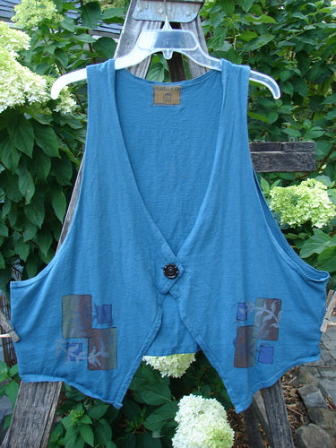 Barclay Calligrapher's Crop Vest Fern Window Blue Tealen Size 1 displayed on a wooden fence, featuring deep arm openings, a single button closure, and dramatic front points.