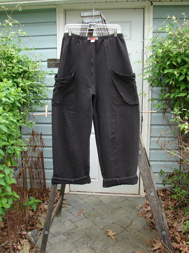 Barclay Interlock Cuff Toboggan Reversible Pant Unpainted Black Size 1 hanging on a wooden ladder, showcasing its fleece cuffed lowers and oversized side pockets.
