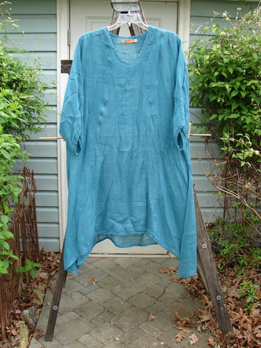 Barclay Linen High Vent Rear Tab Dress Unpainted Turquoise Size 1 hanging on a clothesline, showcasing its A-line shape, curved front seams, and three-quarter length sleeves against an outdoor backdrop.