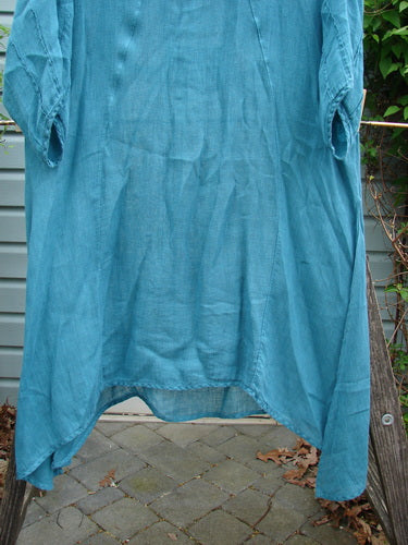 Barclay Linen High Vent Rear Tab Dress Unpainted Turquoise Size 1 hanging on a clothesline, showcasing its curved front seams and tall side vents.