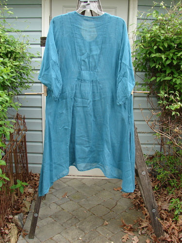 Barclay Linen High Vent Rear Tab Dress Unpainted Turquoise Size 1 displayed on a clothes rack, showcasing its unique curved front seams, three-quarter sleeves, and A-line shape, part of a vintage-inspired collection.