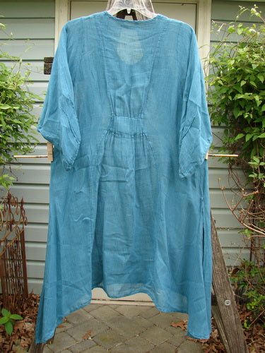 Barclay Linen High Vent Rear Tab Dress Unpainted Turquoise Size 1 displayed on a clothesline, showcasing its elegant curved seams, side vents, pinched sleeves, A-line shape, and varying hemline.