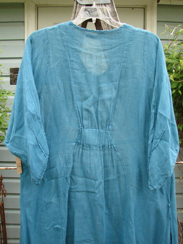 Barclay Linen High Vent Rear Tab Dress in Turquoise Size 1 displayed on a hanger, featuring distinct curved seams, three-quarter sleeves, and a varying hemline, exemplifying Bluefishfinder.com's vintage style.