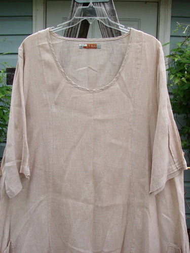 Barclay Linen Drop Pocket Bell Dress Unpainted Sand Size 1 on a hanger, showcasing its A-line shape, pinched three-quarter sleeves, curved seams, and dual drop wrap pockets.