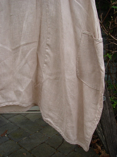 Barclay Linen Drop Pocket Bell Dress Unpainted Sand Size 1 features visible curved seams, three-quarter sleeves, and dual side pockets, emphasizing a flowing A-line with a unique hemline.