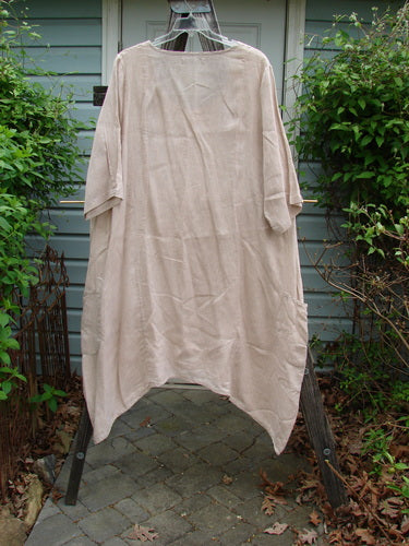 Barclay Linen Drop Pocket Bell Dress Unpainted Sand Size 1 displayed on a clothes rack, highlighting its long, flowing design with unique seams and side vents, part of a vintage-inspired collection.