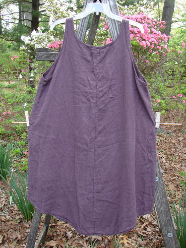 Barclay Linen Round Bottom Primitive Circle Murple Size 1 pinafore draped on a wooden fence, showcasing its unique A-line shape, scoop neckline, and primitive circle pattern detailing.