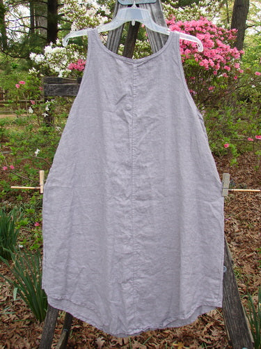 Barclay Linen Round Bottom Pinafore Flying Wing Mallow Size 0 hanging on a clothesline, showcasing its rounded hem and slightly belled side hemline, with a distinctive scoop neckline.