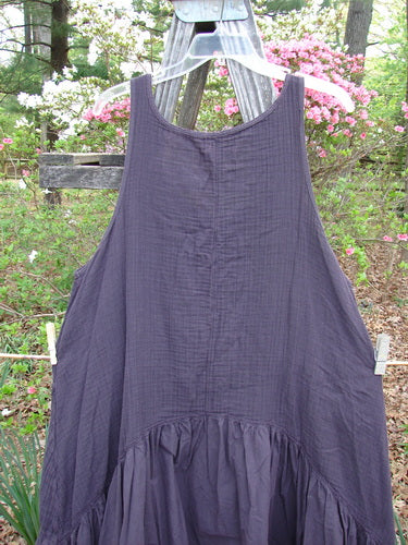 Barclay Gauze Dual Pocket Varano Jumper Unpainted Plum Size 0 displayed on a clothes rack, showcasing its textured upper bodice, deep arm openings, and two exterior pockets, highlighting its unique design.