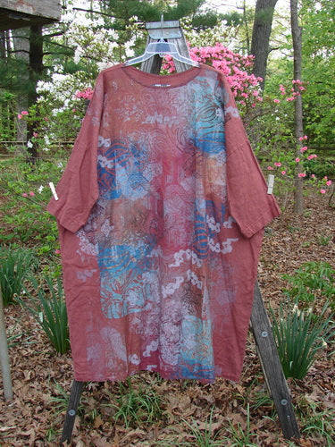 Barclay Linen Oversized Canyon Dress Floral Mountain Brick OSFA hanging outdoors, showcasing its wide straight shape, rounded neckline, three-quarter dolman sleeves, and unique floral mountain pattern design.