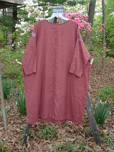 Barclay Linen Oversized Canyon Dress Floral Mountain Brick OSFA displayed on a clothes rack, showcasing its rounded neckline, drop shoulders, and three-quarter dolman sleeves, reflecting Bluefishfinder.com's vintage style.