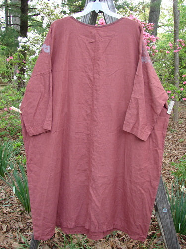 Barclay Linen Oversized Canyon Dress Floral Mountain Brick OSFA hanging outdoors, showcasing its rounded neckline, drop shoulders, and three-quarter length dolman sleeves, highlighting its generous, wide, straight shape.
