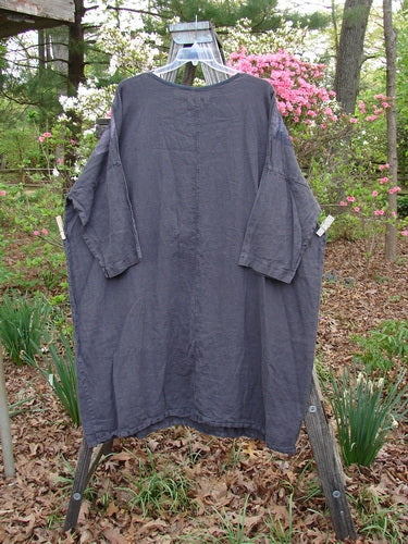 Barclay Linen Oversized Canyon Dress Floral Cityscape Black OSFA, displayed on a clothes rack, features a rounded neckline, drop shoulders, and three-quarter dolman sleeves, embodying vintage Blue Fish Clothing’s creative aesthetic.