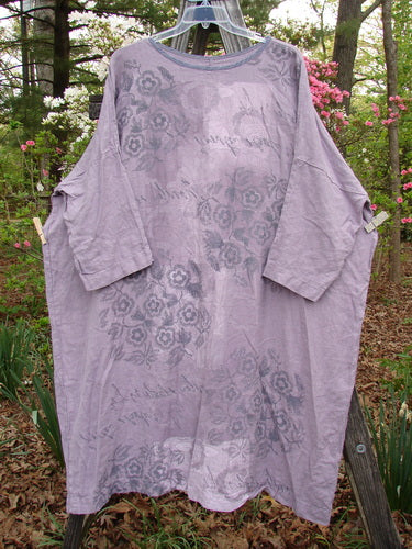 Barclay Linen Oversized Canyon Dress Floral Garden Lilac OSFA hanging on a clothesline, showcasing its rounded neckline, three-quarter dolman sleeves, and floral pattern, representing BlueFishFinder's unique vintage style.
