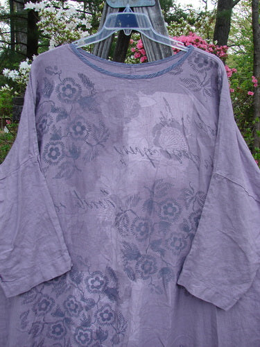 Barclay Linen Oversized Canyon Dress Floral Garden Lilac OSFA displayed on a hanger, featuring a floral pattern, rounded neckline, drop shoulders, and three-quarter dolman sleeves, highlighting the dress's generous straight shape.