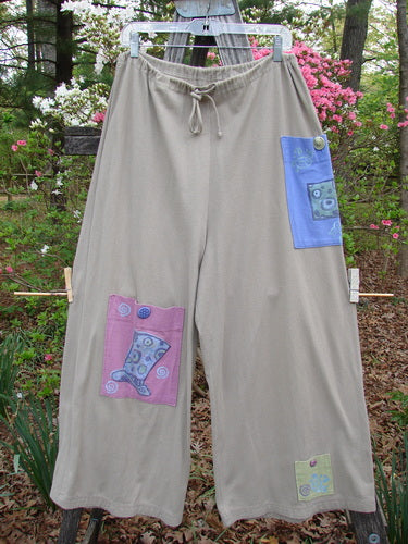 1997 Cubist Pant Top Hat Wheat Altered Size 1, featuring patchwork designs, multiple oversized pockets, and chunky buttons, hanging from a clothesline.