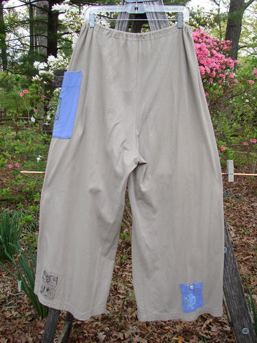 1997 Cubist Pant Top Hat Wheat Altered Size 1 displayed on a clothesline, showcasing its oversized pockets and wide, belled shape with distinctive vintage buttons and drawstring waist.