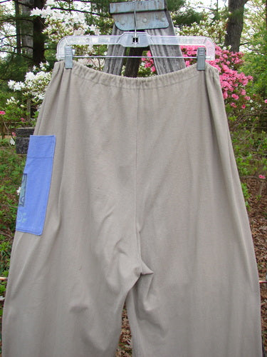 1997 Cubist Pant Top Hat Wheat Altered Size 1 hanging on a clothesline, showcasing its wide shape, oversized pockets, and vintage blue buttons, embodying Bluefishfinder.com's unique vintage style.