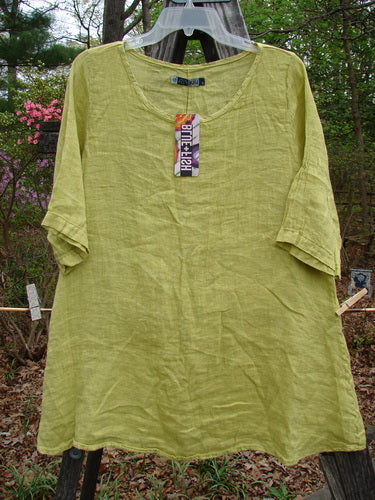 Barclay NWT Linen Springtime Top in Citron hanging on a clothesline, showcasing its rounded neckline, flowy A-line shape, and almost three-quarter length sleeves.