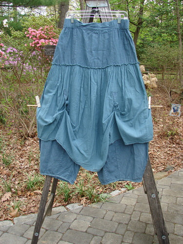 Barclay Linen Batiste Fusion Pant Skirt Unpainted Teal Size 0 displayed on a wooden stand, showcasing its layered design and dual tie accents, embodying BlueFishFinder's vintage aesthetic.