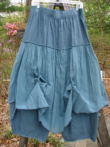 Barclay Linen Batiste Fusion Pant Skirt Unpainted Teal Size 0 displayed outdoors, showcasing its unique double tie accents, triangular patches, and slightly billowy shape over a contrasting cropped under pant.